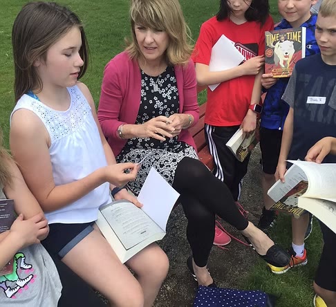 Maureen McQuerry reading and talking with students outdoors